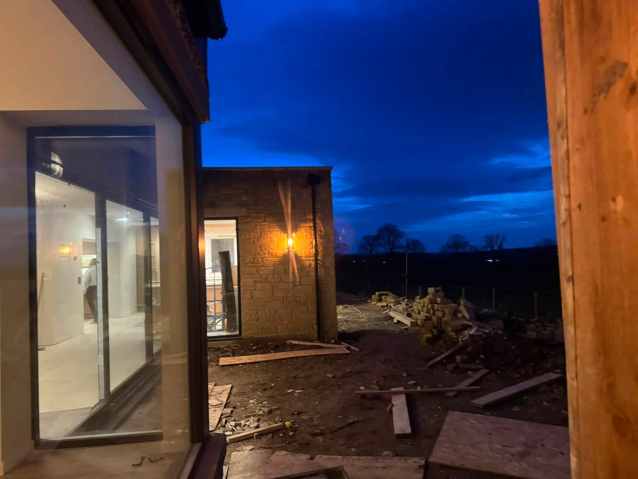 Exterior lighting at dusk on a property with surroundings still being finished